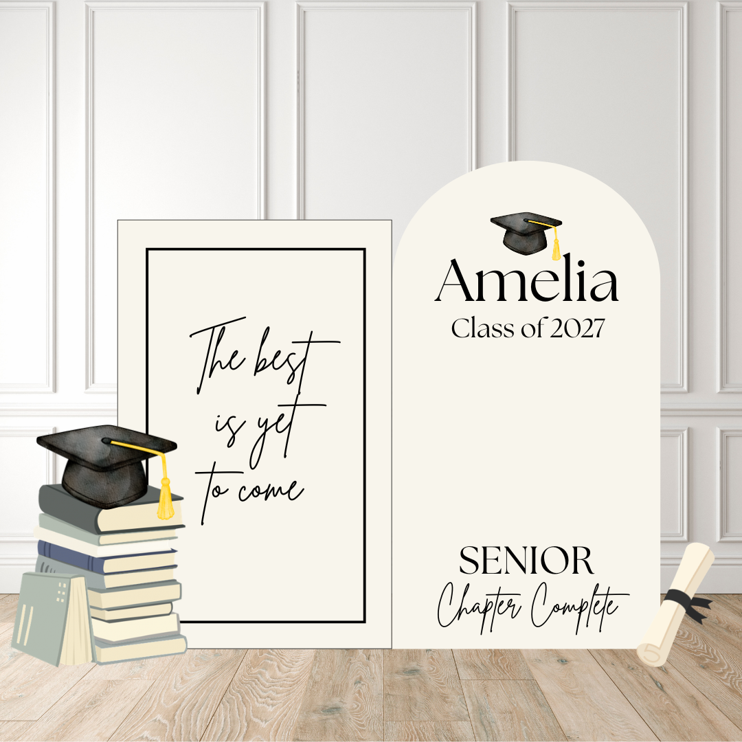Personalized graduation-themed decorative signs displayed on a light wood floor against a white paneled wall. The set includes a rectangular sign with the phrase 'The best is yet to come,' an arched sign reading 'Amelia Class of 2027' and 'SENIOR Chapter Complete' with a graduation cap illustration, a stack of books with a graduation cap on top, and a rolled diploma.