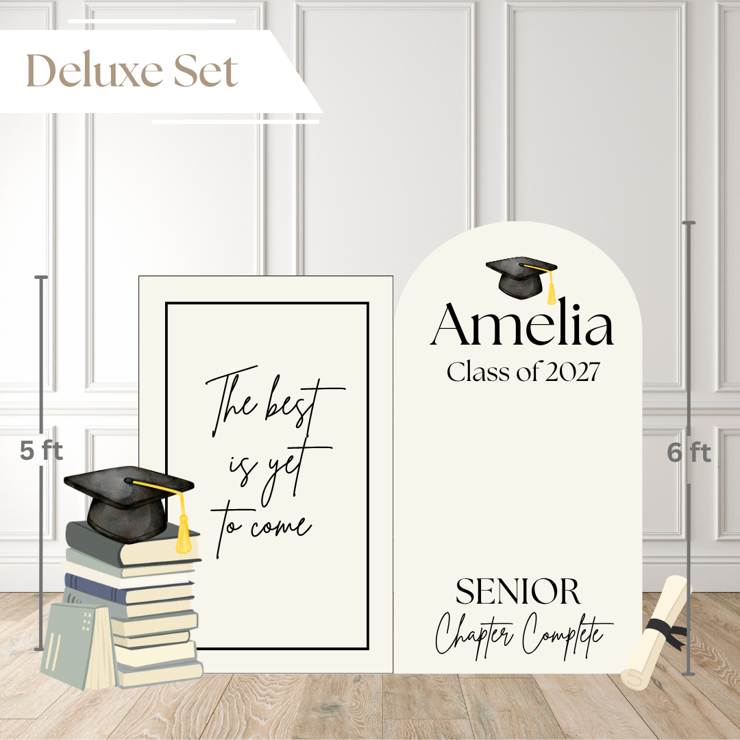 Deluxe set graduation backdrop and matching signs shown in a room mockup. The set includes a tall arched backdrop reading 'Amelia Class of 2027' and 'Senior Chapter Complete,' a smaller rectangular sign reading 'The best is yet to come,' a stack of books with a graduation cap illustration, and a diploma scroll.