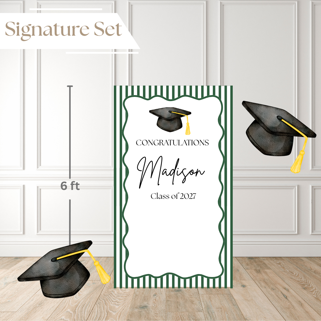 Graduation party backdrop set featuring a large vertical congratulatory sign with a green striped border and two black graduation caps with yellow tassels on a white paneled wall and wood floor. A small 'Signature Set' label appears in the top left, and a height marker indicates 6 ft.